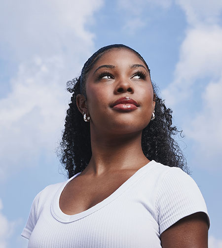 student looking up with the skies behind her