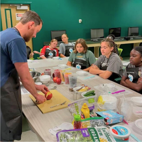 Man showing how to prep food in front of children