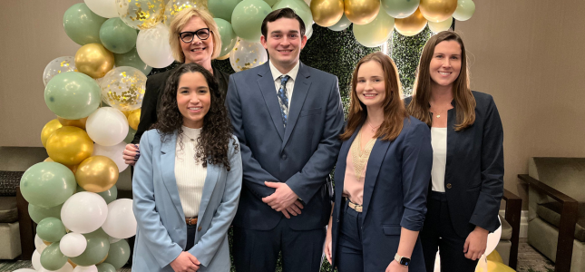 Four Leadership students and Kay Thiemann standing in front of gold and green baloons