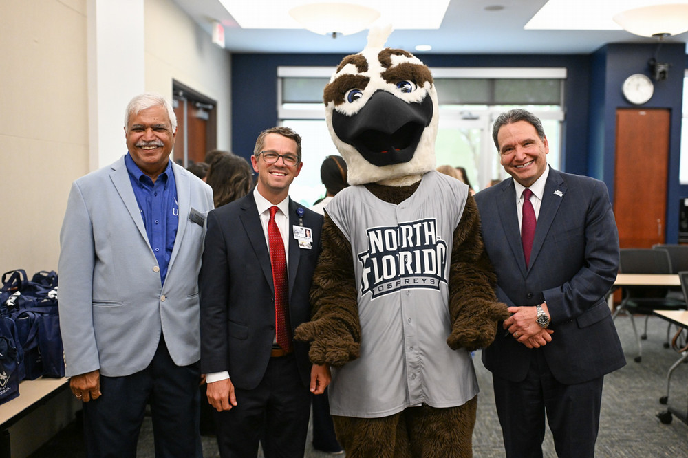 UNF mascot with three leaders at campus event in meeting room