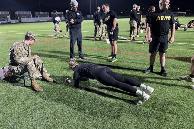 Gabby participating in an Army fitness test by holding a plank in the grass