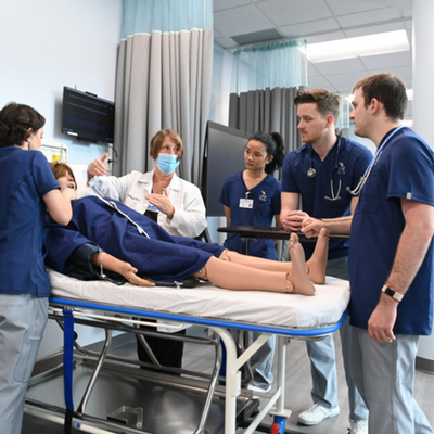 4 nursing students and 1 nursing faculty with a mannequin