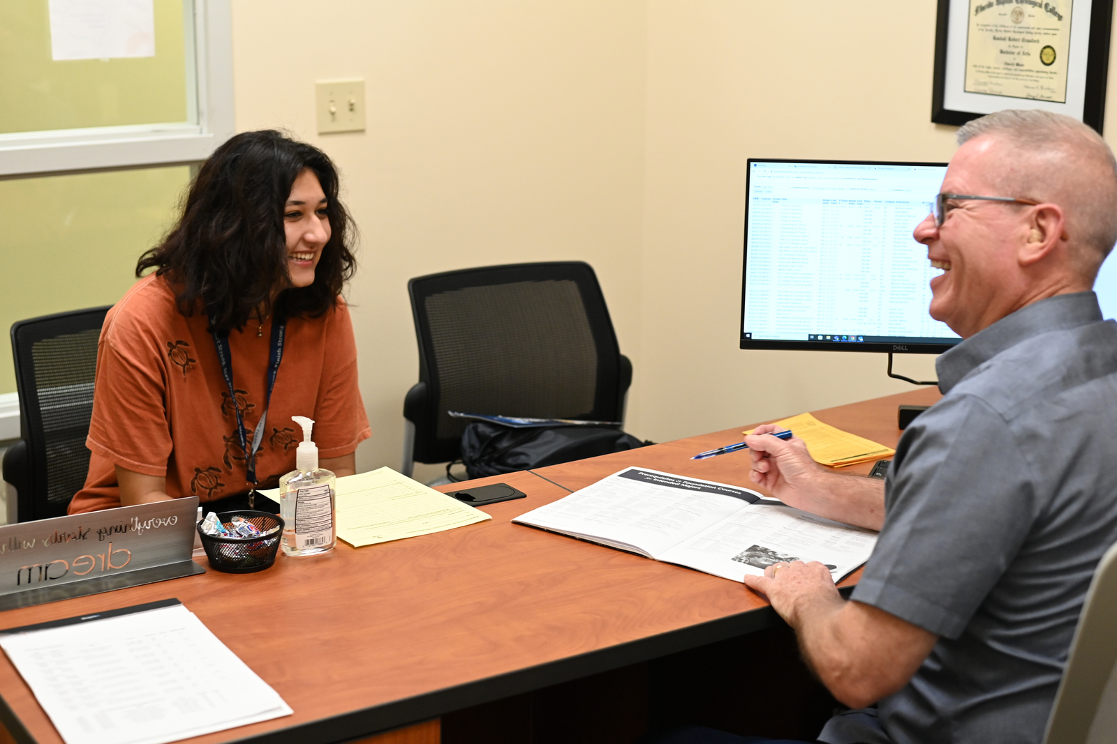 Student talking with her academic advisor at a desk