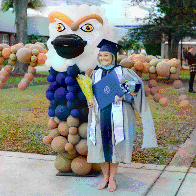 BCH student standing in front of osprey graduation balloon display