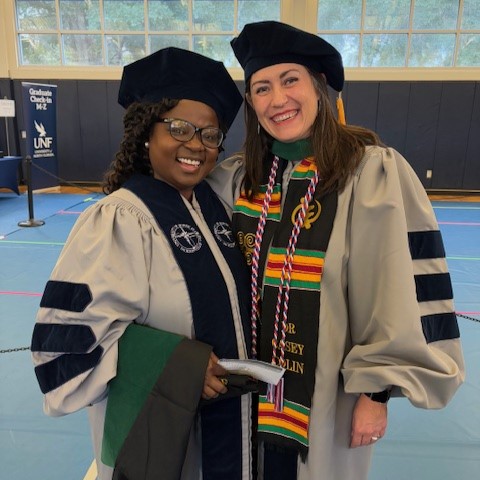 Casey Collin and a UNF students wearing graduation attire smiling