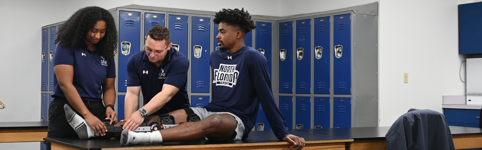 Athletic training students apply knee brace to student on table