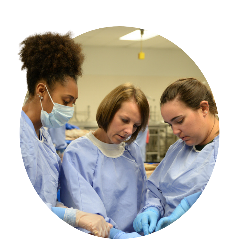 Athletic Training Faculty Michelle Boling with two MS students in a lab with lab coats and cloves on.