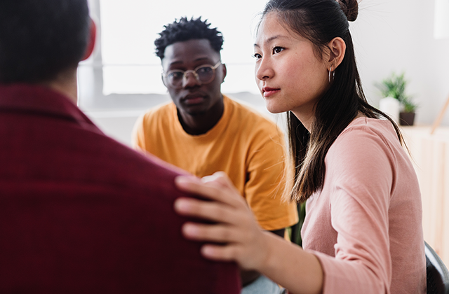 three people in a counseling session with woman touching a man's shouldar