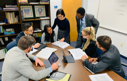 people gathered around a meeting desk looking at documents