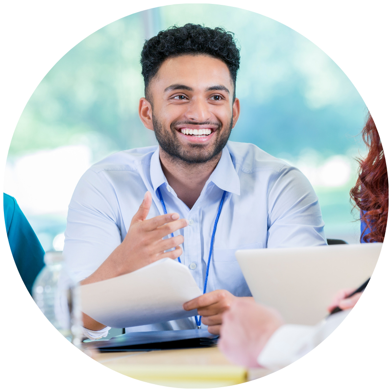health admin student at a table holding a piece of paper and wearing a dress shirt.