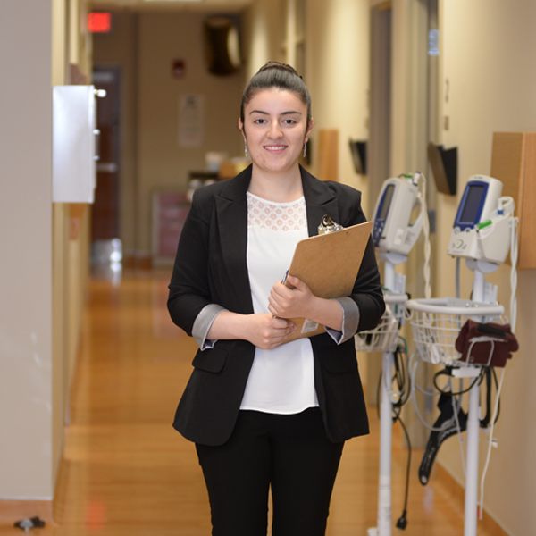 student standing in a medical facility hallway with a folder