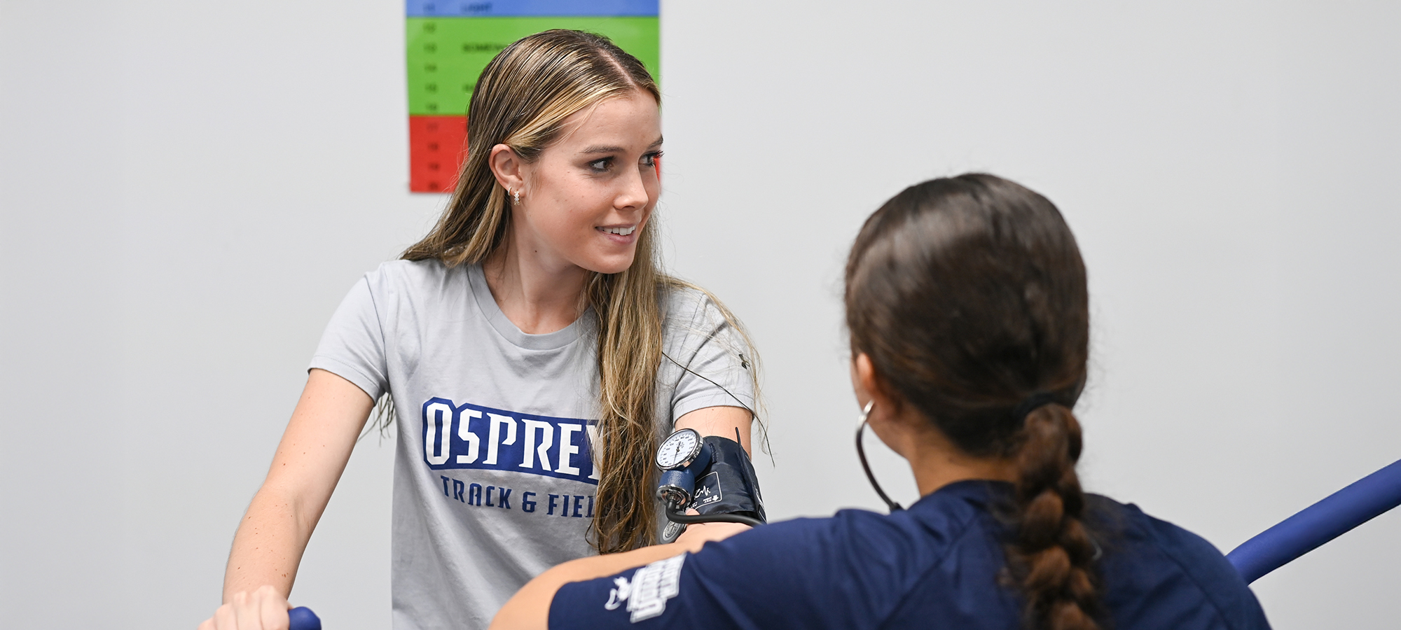 student athlete on a treadmill while another student checks vitals