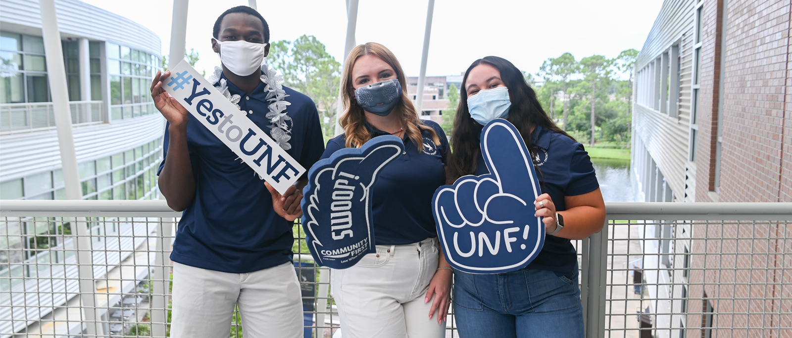 three students holding signs saying yes to unf swoop and unf