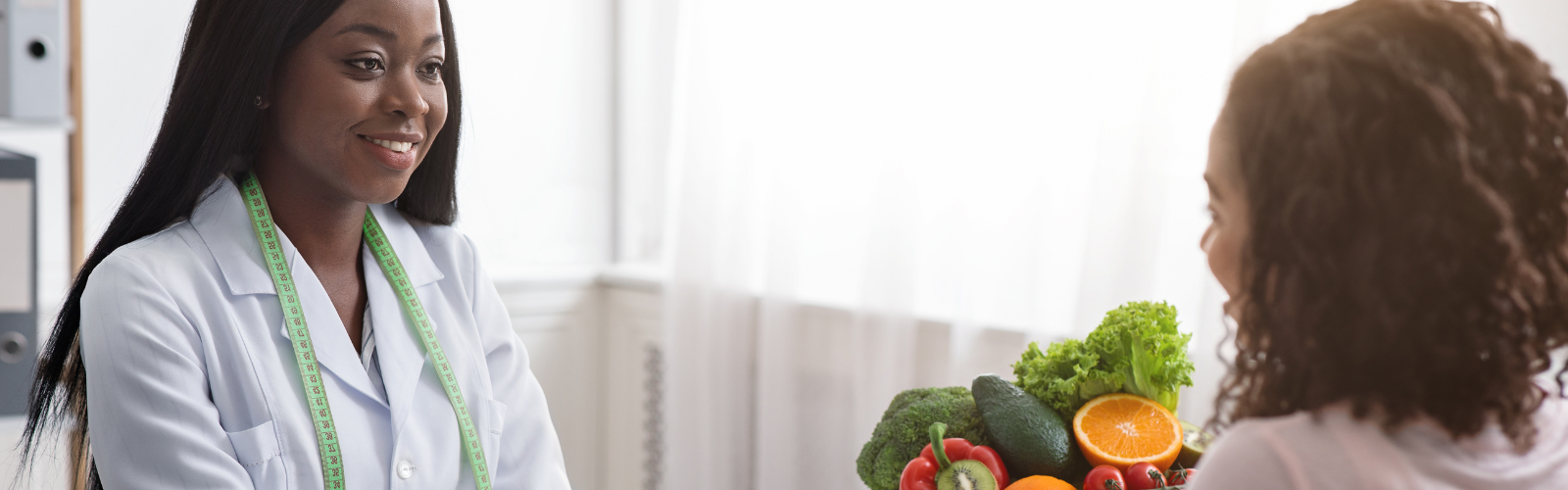 Dietitian talking with a client.  Bowl of fruit on the table. 