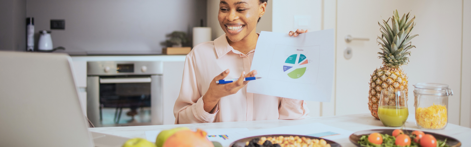 women holding a food chart and a pen talking on the computer