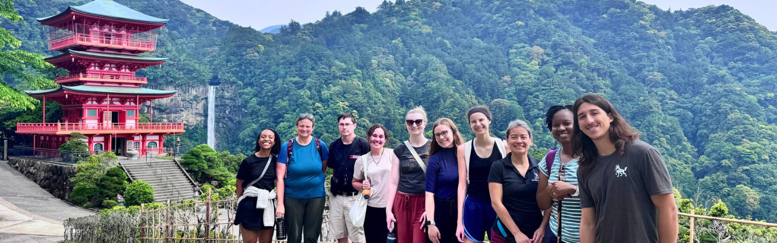 UNF nutrition and dietetics students and faculty standing in front of a red pagoda temple and waterfall in Japan.