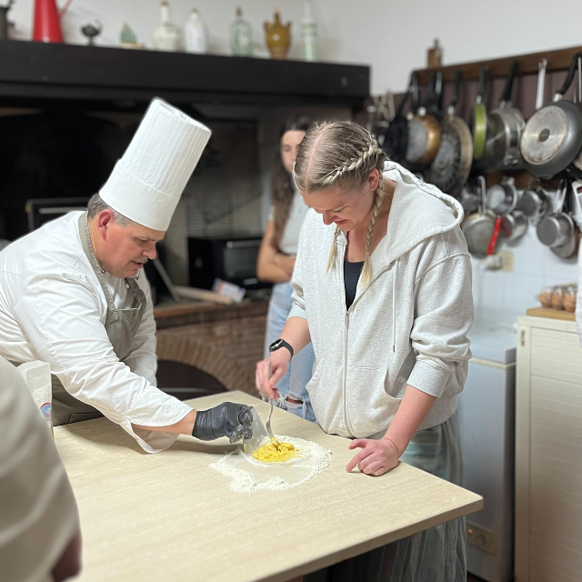 Chef instructing student in pasta making in kitchen