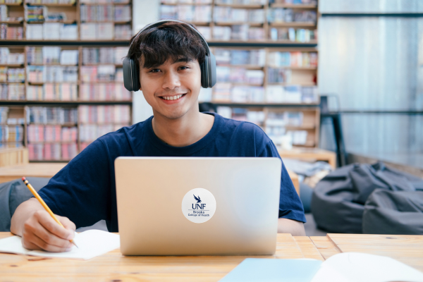 Male student virtual studying at a library with laptop