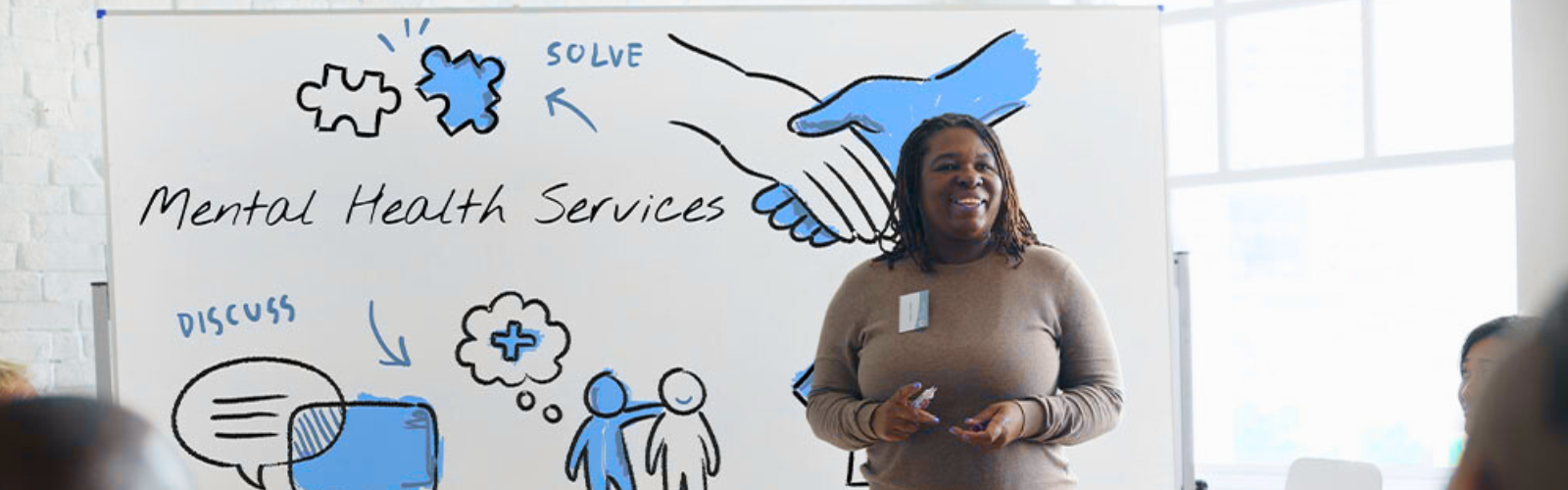 Public Health professional standing in front of a white board that says Mental Health Services