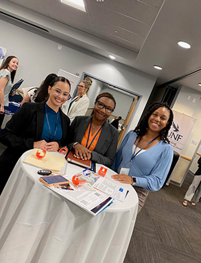 three students standing at a table at an event