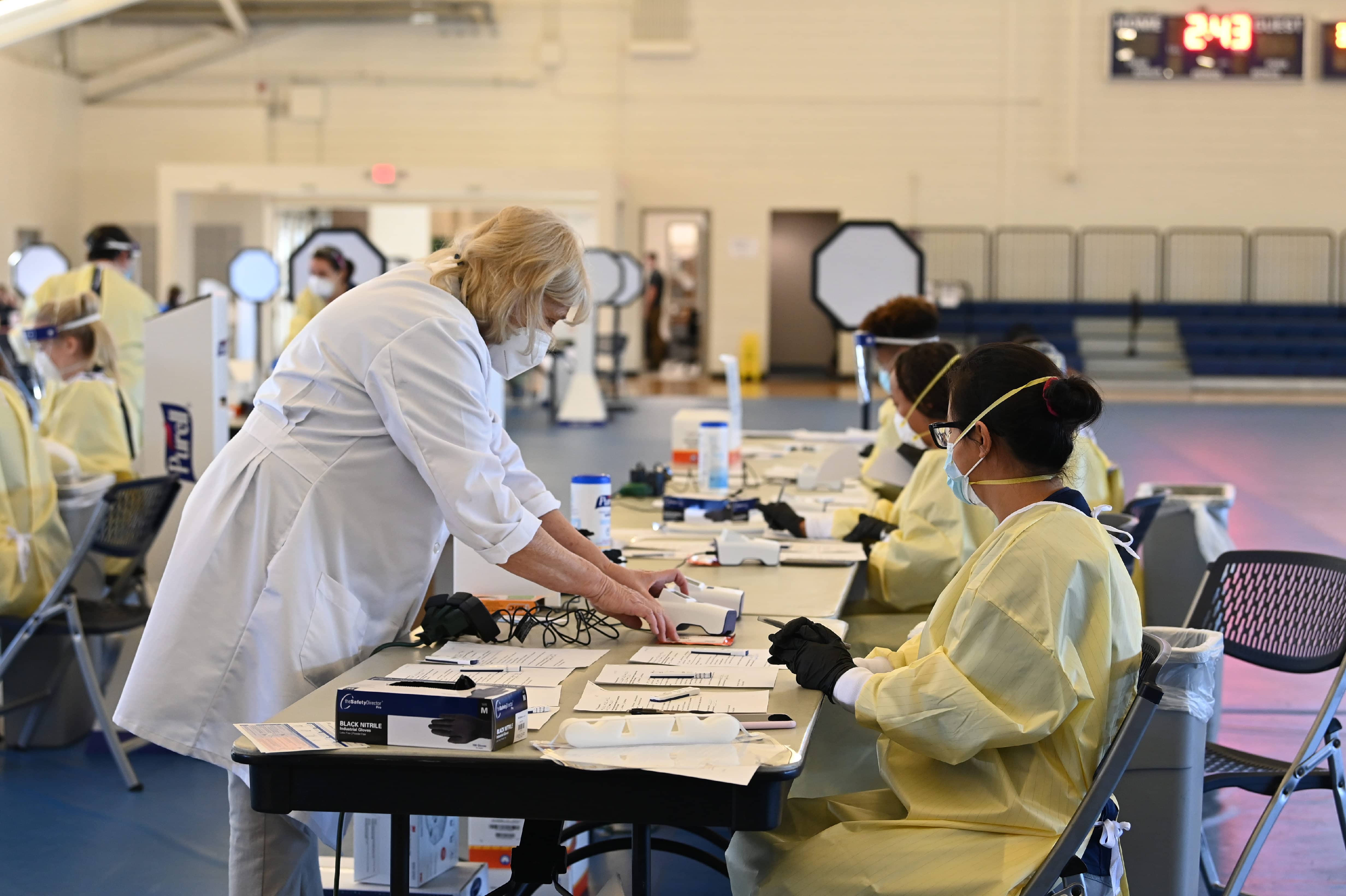 Professor in lab coat demonstrating medical equipment to students in sterile uniforms