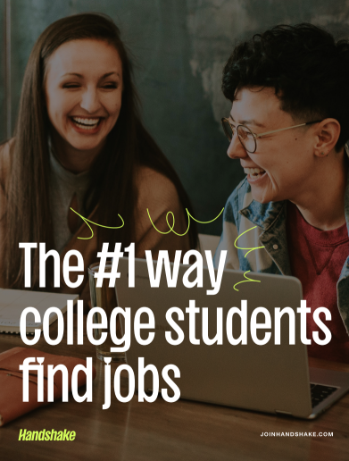 Two students laughing while looking at a laptop