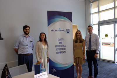 Professional u panel guests standing by banner
