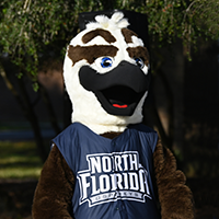 Ozzie Osprey standing in front of some trees