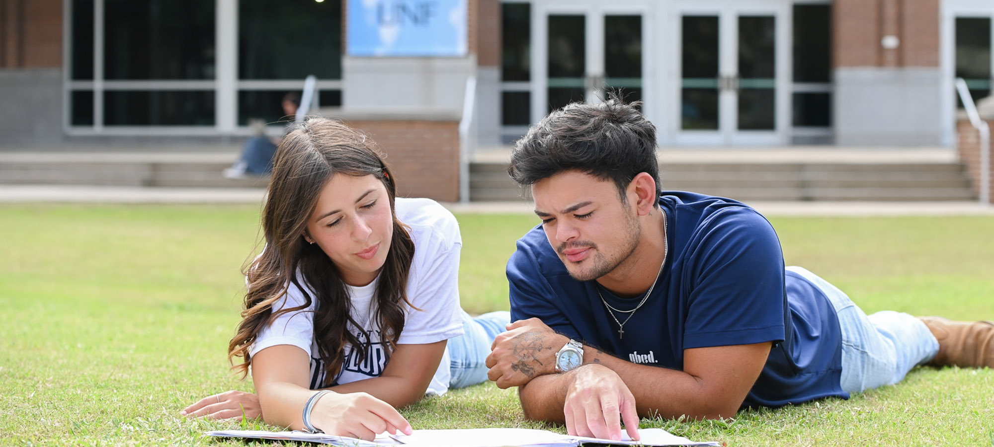 two students studying on the lawn