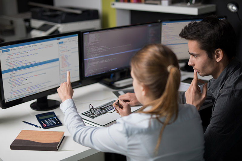 two students looking through computer code