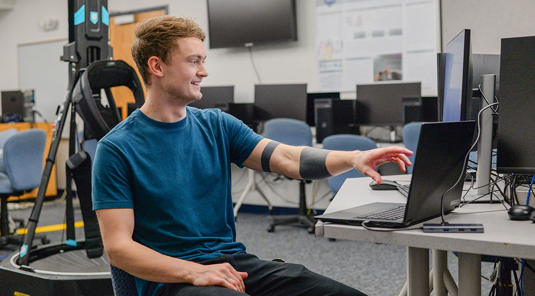 student smiling while working on a laptop