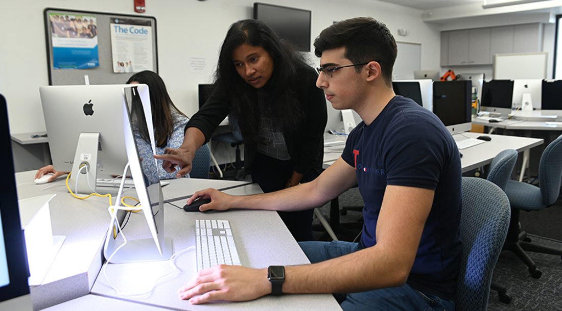 Student and professor working on a computer in a classroom