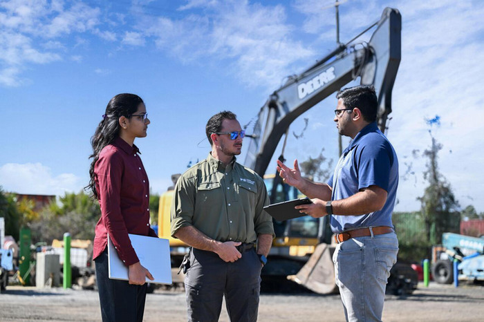 CCEC students and Dr. Kalasapudi standing a talking together in front of heavy machinery.