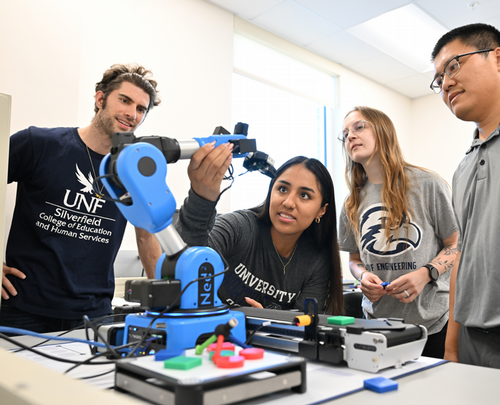 Dr. Longfei Zhou and students in a UNF lab with a robot arm
