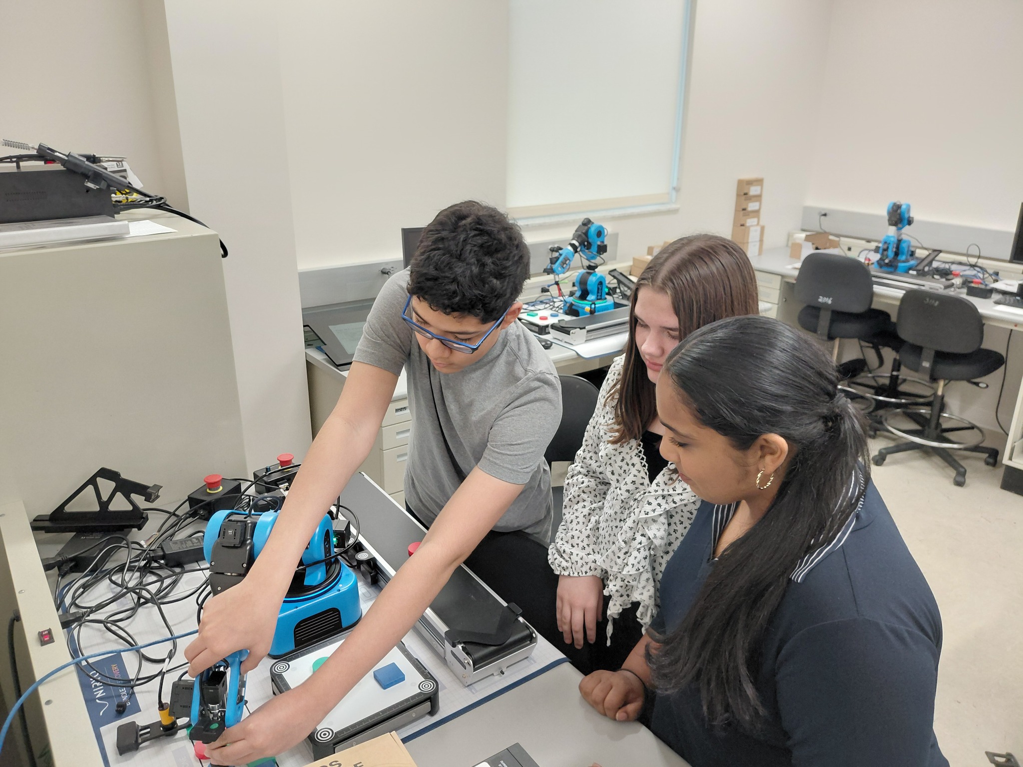 Three students working with robotics tools