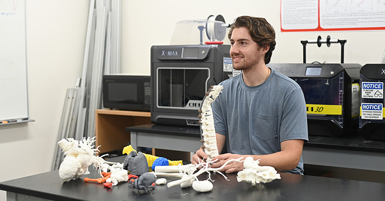 student smiling with 3d printed pieces