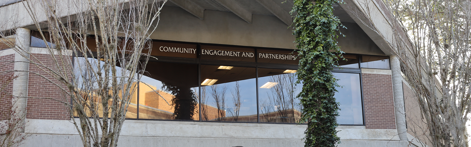 The windows of the office of Community Engagement and Partnerships with the name across the top
