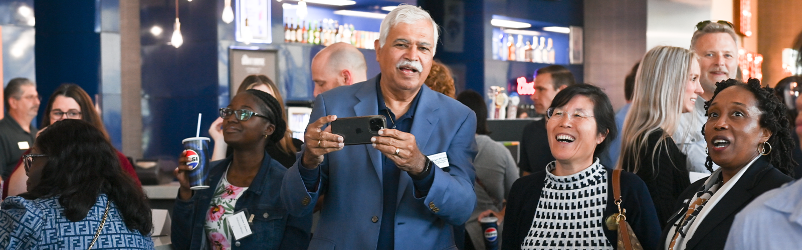Group of people watching and having fun with one person holding their iPhone to take a picture.