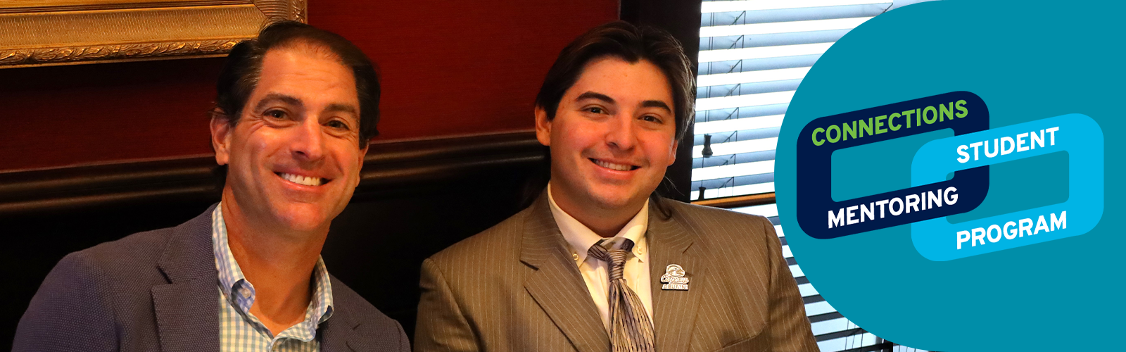 Mentor and mentee wearing suits and smiling with the Connections logo to the right