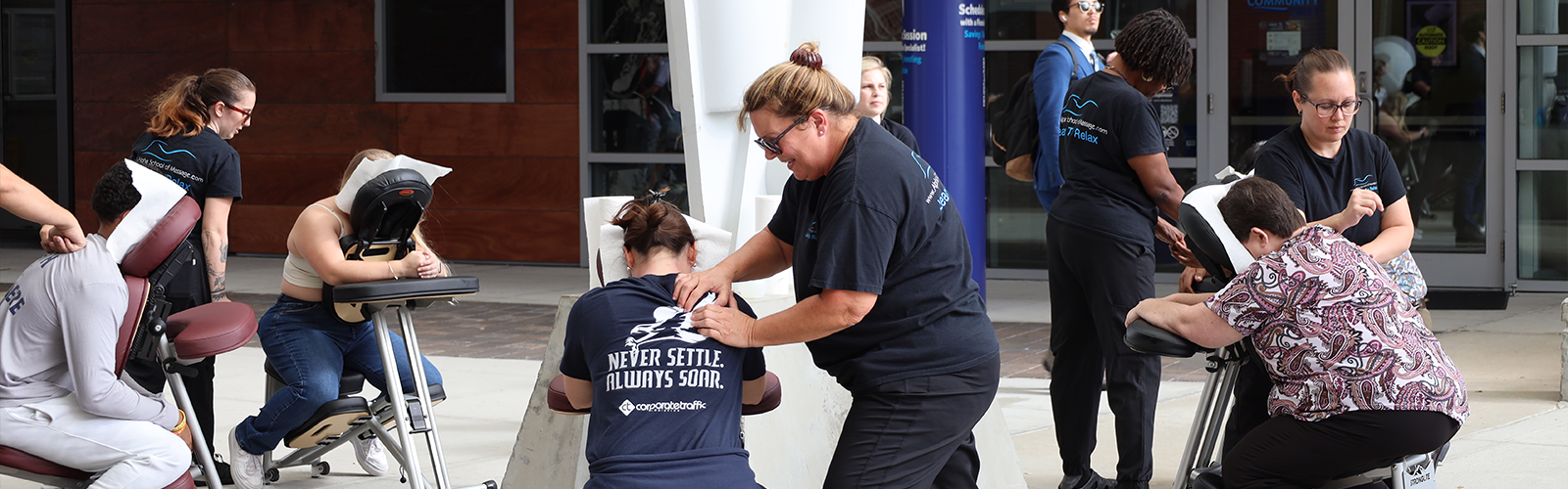 Student and staff getting message with the center person's shirt read 'Never Settle. Always Soar.'