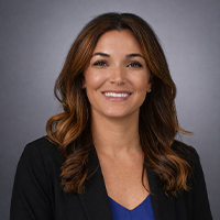 Ally smiling and wearing a black suit jacket with a blue blouse