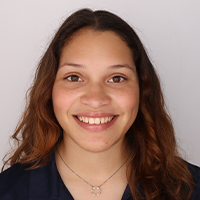 Tatiana smiling and wearing a blue shirt and silver necklace