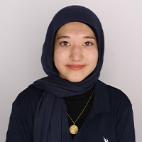 Tayebe smiling wearing a blue shirt, blue hijab, and gold necklace