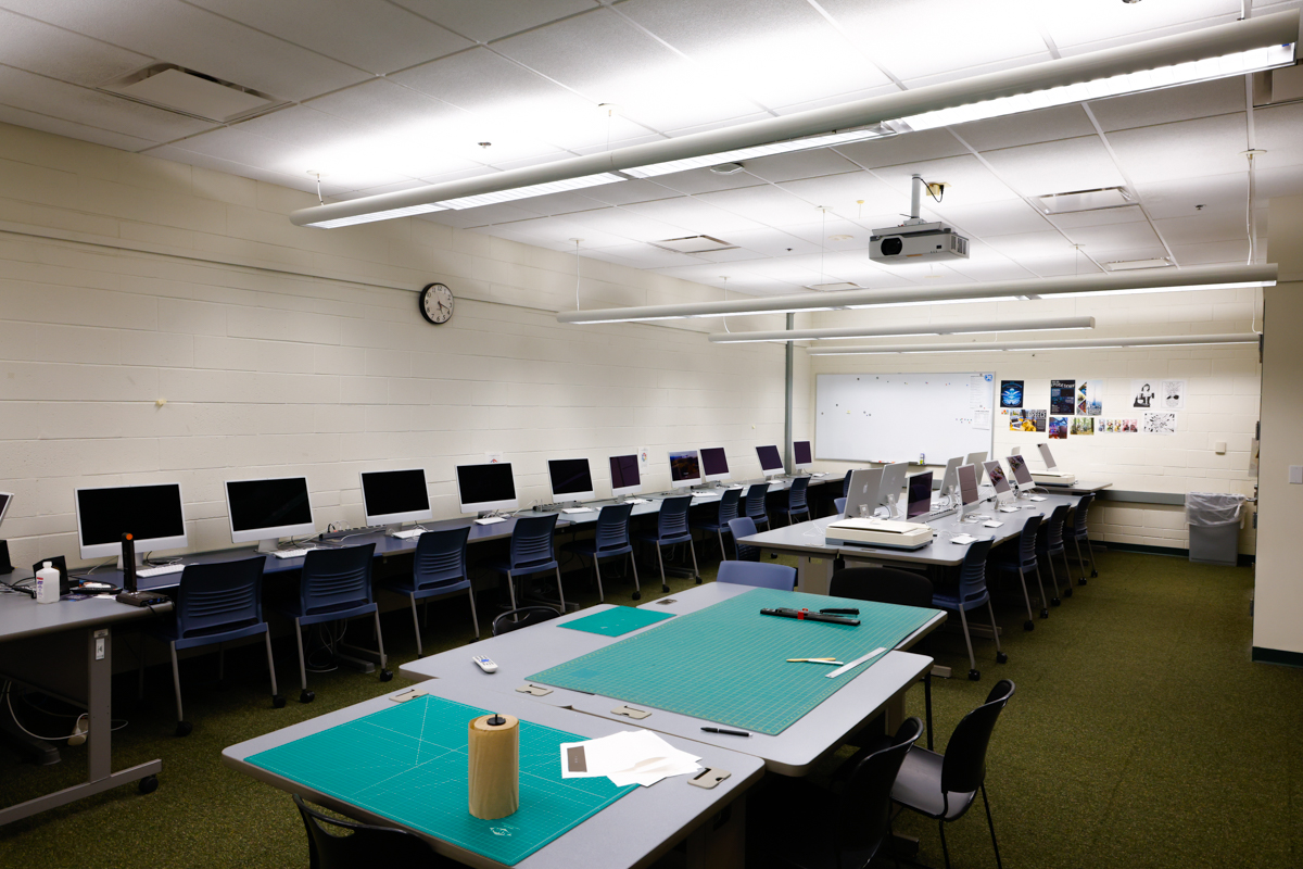 Classroom with desktop computers and worktables with green cutting mats.