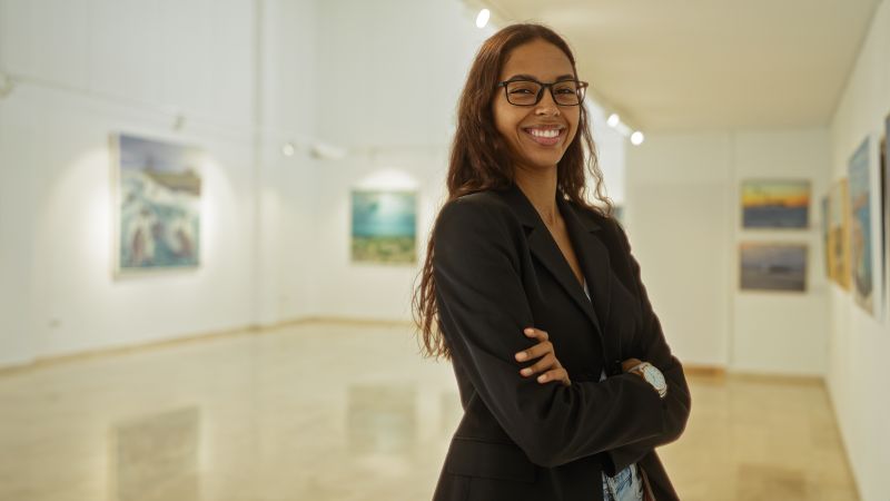 Student smiles in a gallery filled with artwork