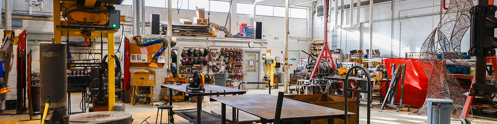 Industrial fabrication lab with welding equipment, tools, machinery and student work areas