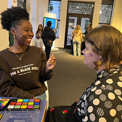 student drawing a face painting design on someone else