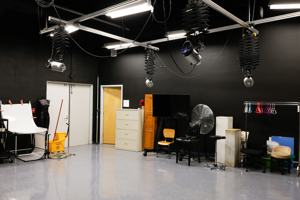 A photography studio with various lighting equipment, a mannequin, and furniture, showcasing a space designed for creative production.