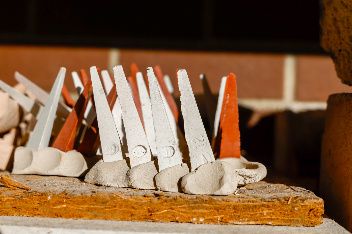 Ceramic clay tools arranged on a wooden surface, featuring a mix of gray and red colors.