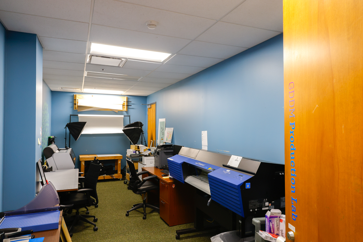 Interior view of a production lab featuring workstations, printers, and photography equipment.